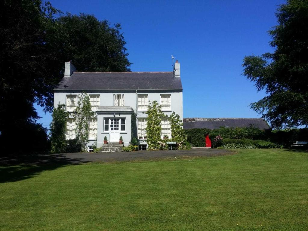 duży biały dom z dużym zielonym trawnikiem w obiekcie Dromore House Historic Country house w mieście Coleraine