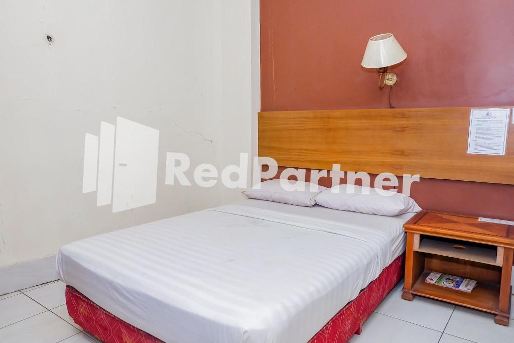 - une chambre avec un lit doté d'une tête de lit en bois et d'une table dans l'établissement Hotel Sebelas At Jalan Palasari Mitra RedDoorz, à Bandung