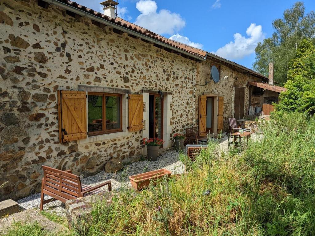 a stone house with benches in front of it at Gîte Massignac, 4 pièces, 6 personnes - FR-1-653-213 in Massignac