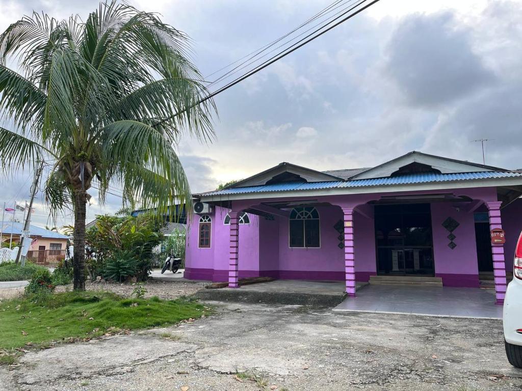 a pink house with a palm tree in front of it at Roomstay Budget Kuala Terengganu Desa Chendering Private Bathroom in Kuala Terengganu