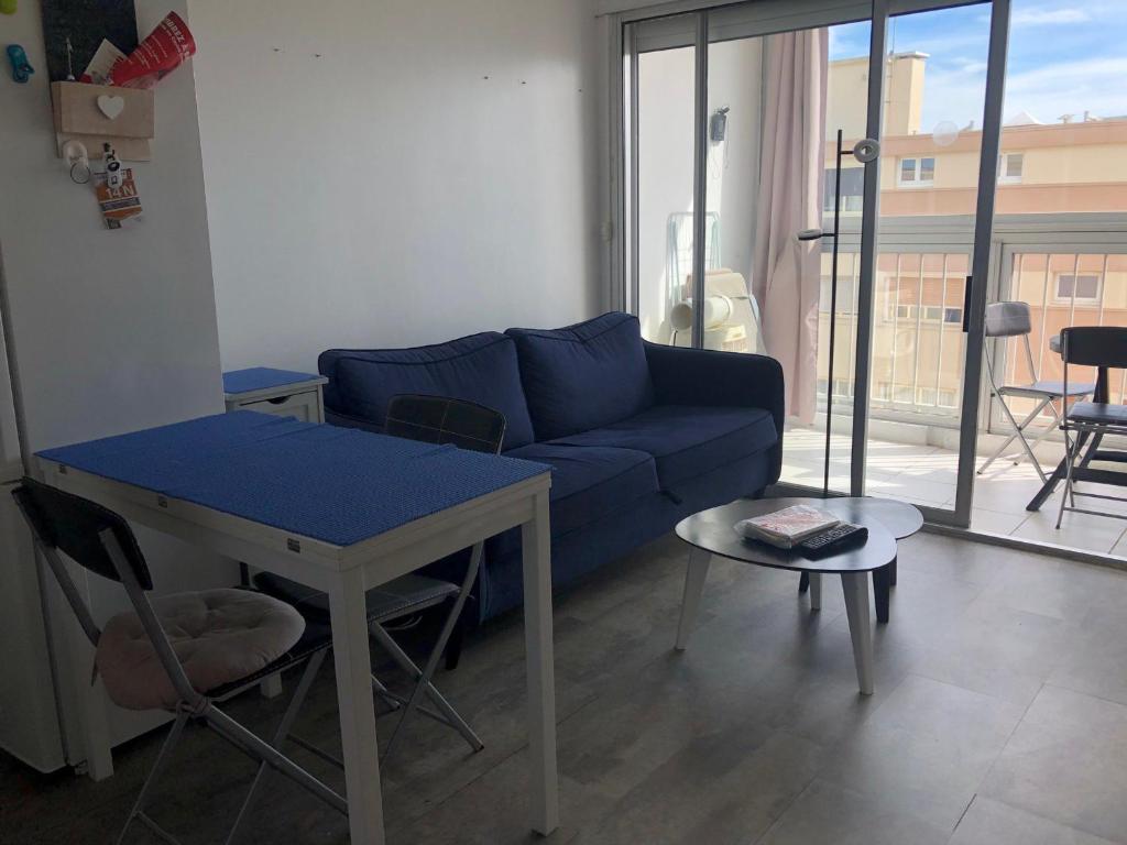 salon z niebieską kanapą i stołem w obiekcie Appartement avec Balcon Proche des Thermes, Étang et Commerces - Climatisé, Animaux Admis - FR-1-503-134 w mieście Balaruc-les-Bains