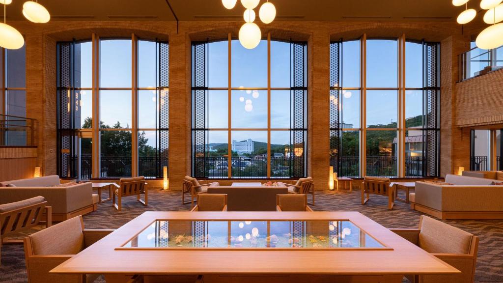 鳥羽市にある亀の井ホテル 鳥羽のテーブルと椅子、大きな窓が備わる広い客室です。