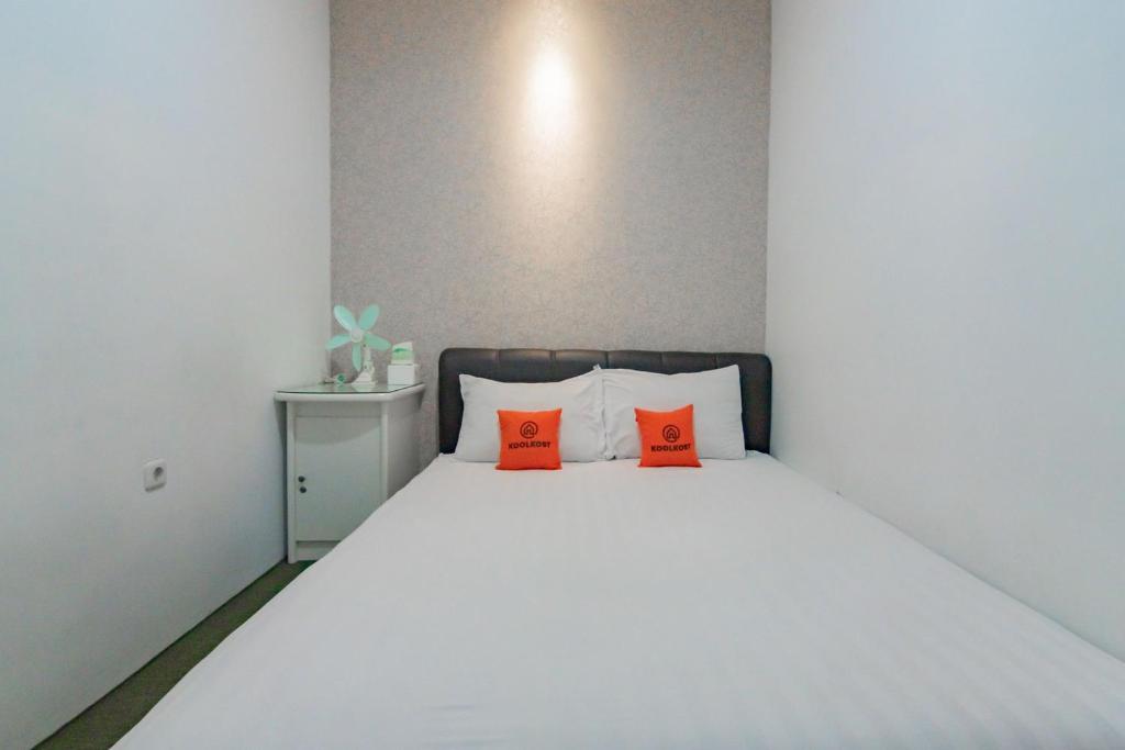 um quarto com uma cama branca e almofadas laranja em KoolKost near Cihampelas Walk em Bandung