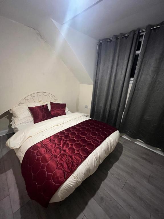 um quarto com uma cama grande com lençóis e almofadas vermelhas em Double Bedroom in West Yorkshire, Leeds em Hunslet