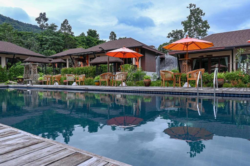 a swimming pool with chairs and umbrellas next to a house at Cascade Tara in Na Mueang