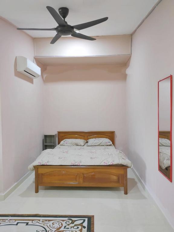 a bedroom with a bed with a ceiling fan at Hidden Homestay in Marang