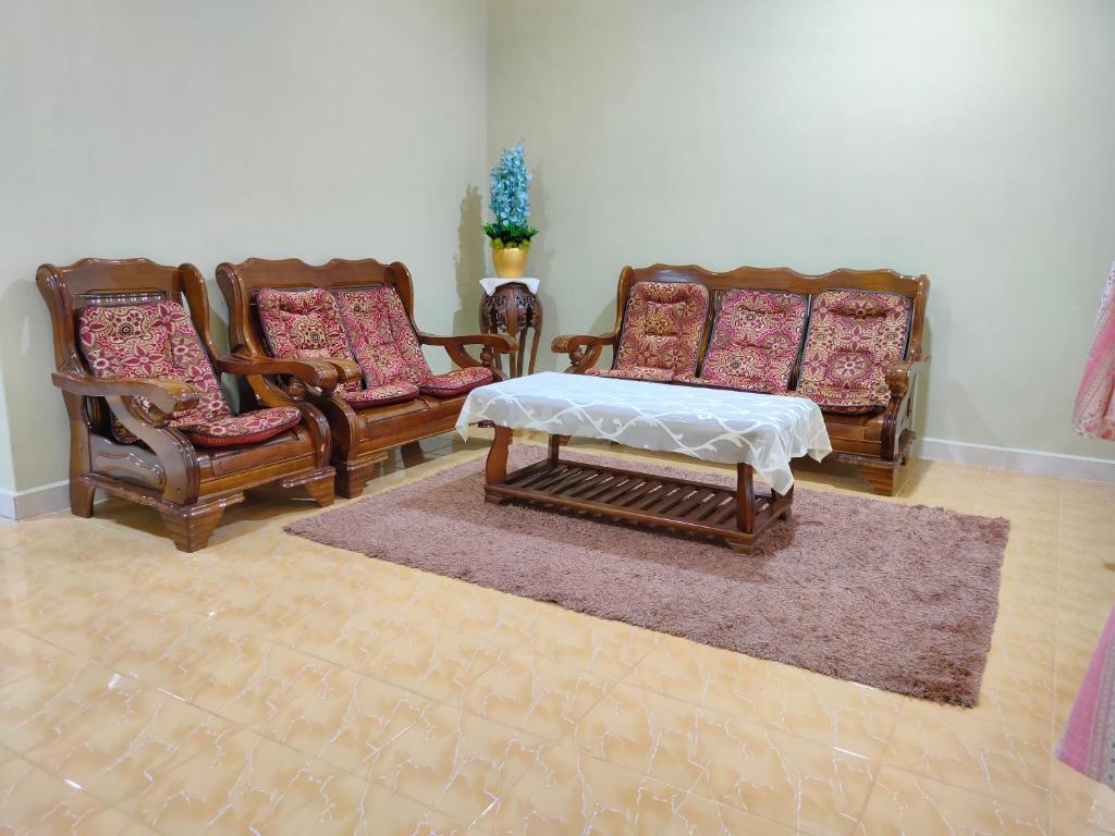 a living room with three chairs and a table at Hidden Homestay in Marang