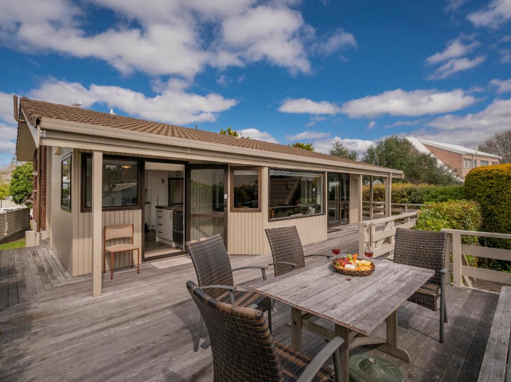 a deck with a table and chairs and a house at Relax On Courtney - Pauanui Holiday Home in Pauanui