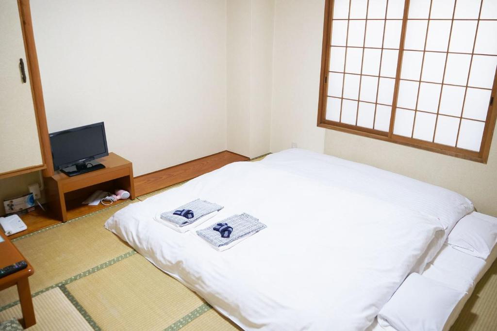 Anan Daiichi Hotel - Vacation STAY 22204v في Anan: غرفة صغيرة فيها سرير وتلفزيون
