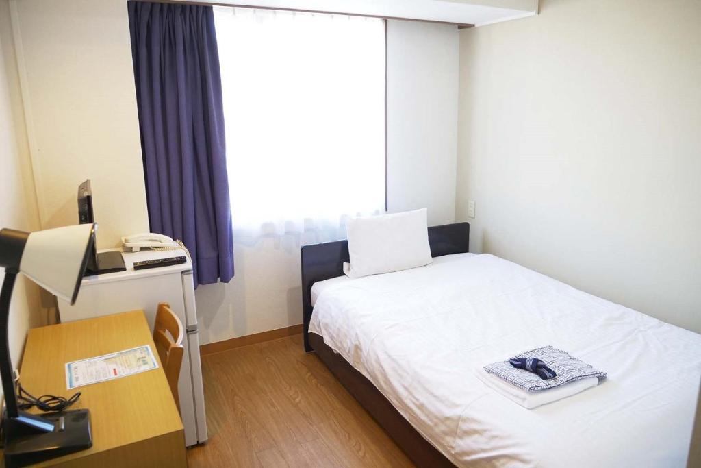 a room with a bed and a desk and a window at Anan Daiichi Hotel - Vacation STAY 55570v in Anan