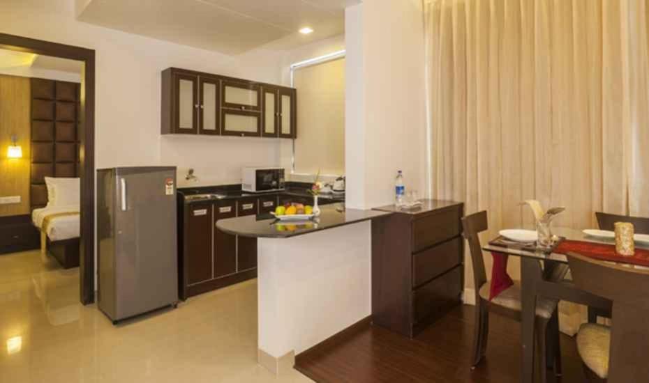 a kitchen and living room with a refrigerator and a table at Hotel DORTN in Pune