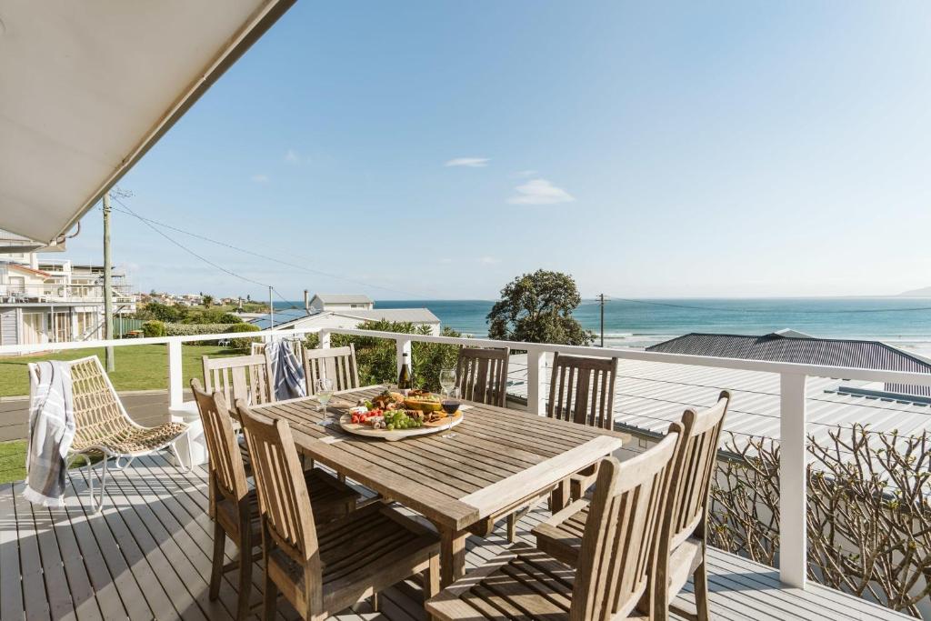 een houten tafel en stoelen op een terras met uitzicht op de oceaan bij The G At Gerroa in Gerroa