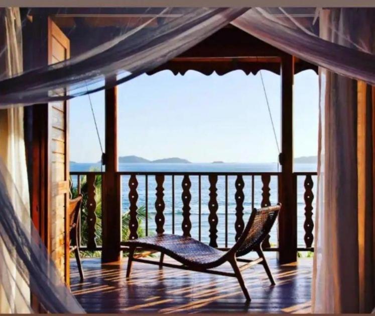 a chair on a porch with a view of the ocean at Lakaz An Bwa in La Digue