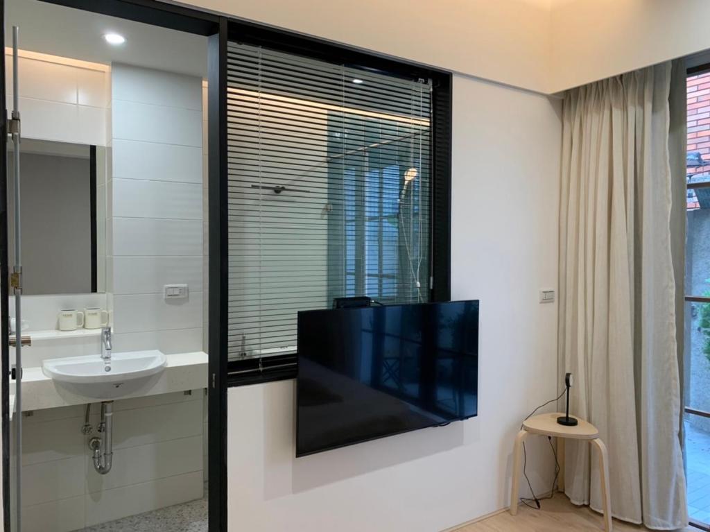 a bathroom with a tv on a wall with a sink at HoME-Easyhouse-III in Tainan