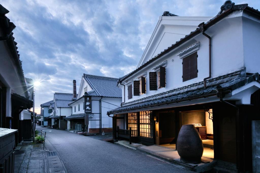 una calle vacía en una ciudad con edificios blancos en 茜さす 肥前浜宿 Akanesasu Hizenhamashuku, en Hama