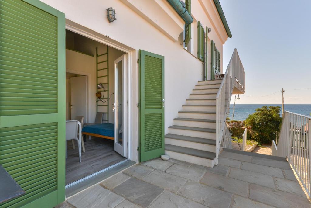 uma casa com portas verdes e escadas que levam ao oceano em Il Quartiere apt Capraia em Pomonte