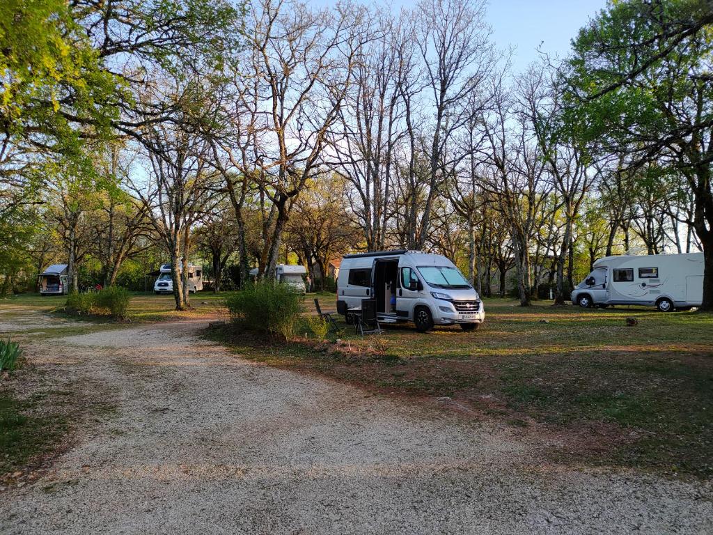 a white van parked in a field next to trees at CAMPING LE BEL AIR Mobil home L&#39;OLIVIER 4 personnes in Limogne-en-Quercy