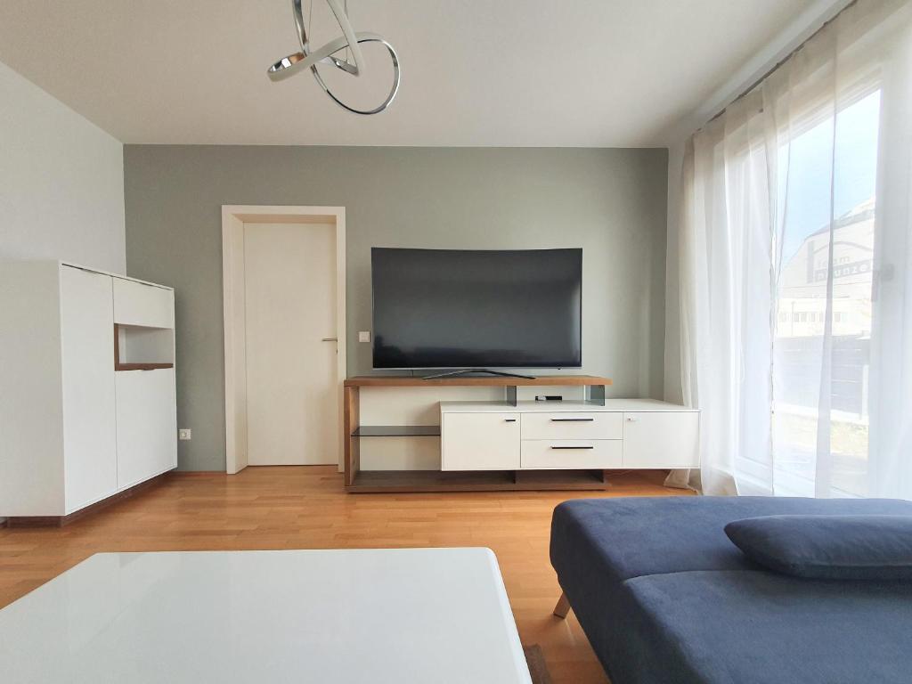 un salon avec une télévision à écran plat sur une armoire blanche dans l'établissement Near Lake Spacious & Furnished Beautiful Apartment, à Vienne