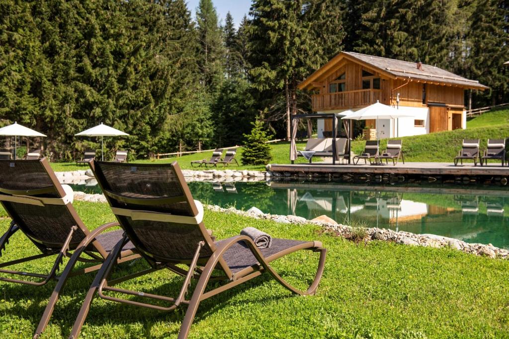 dos sillas de jardín sentadas en el césped junto a una piscina en Lerchpeuntgut Alpenfreud Apartments, en Tamsweg