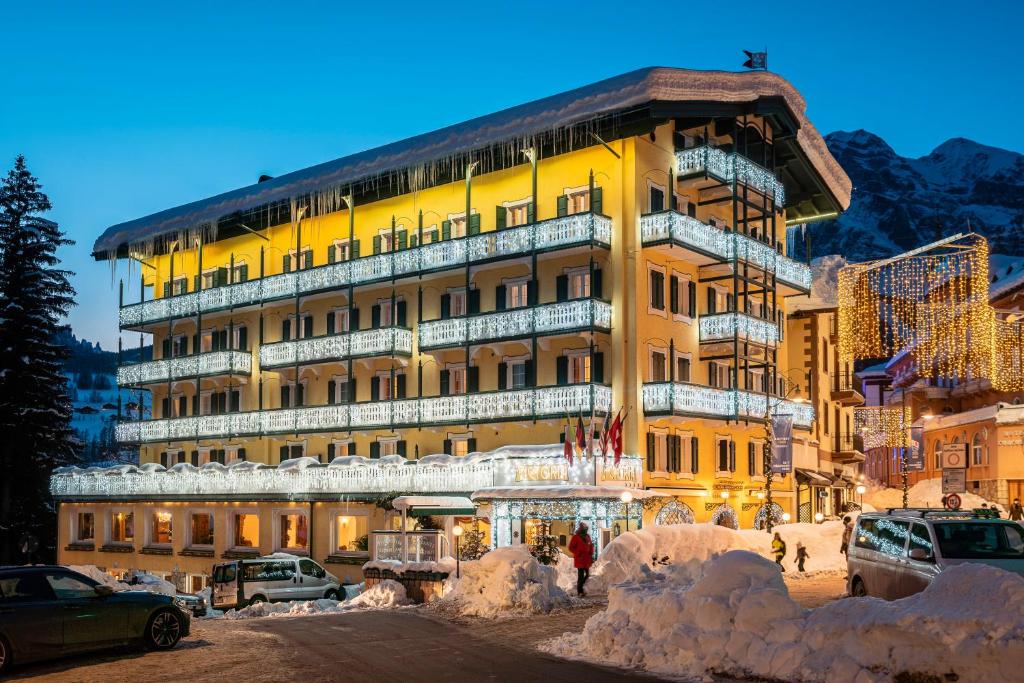 un gran edificio amarillo con nieve delante en Parc Hotel Victoria, en Cortina dʼAmpezzo