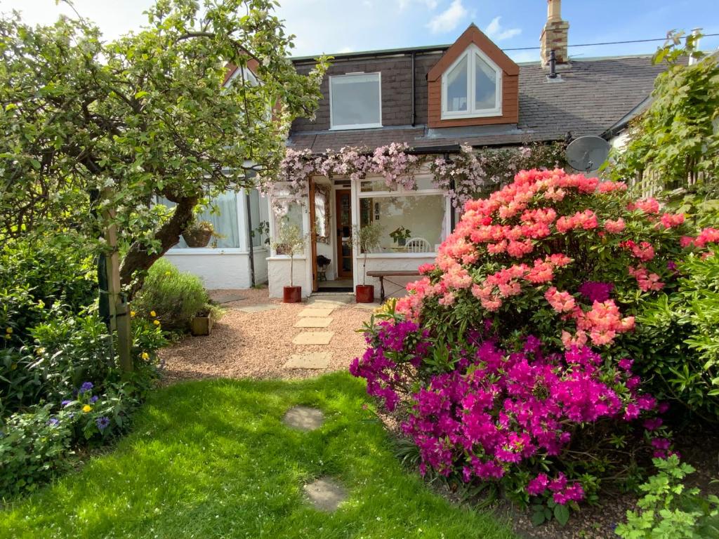 a home with flowers in the yard at The Nest- Cosy Holiday Cottage in Errol