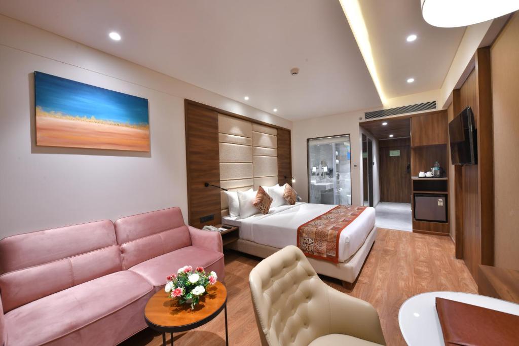 een hotelkamer met een bed en een bank bij Regenta Fairlark Vadodara in Vadodara