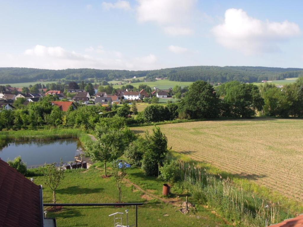a view of a field and a town with a pond at Ferienwohnung Rose in Preußisch Oldendorf