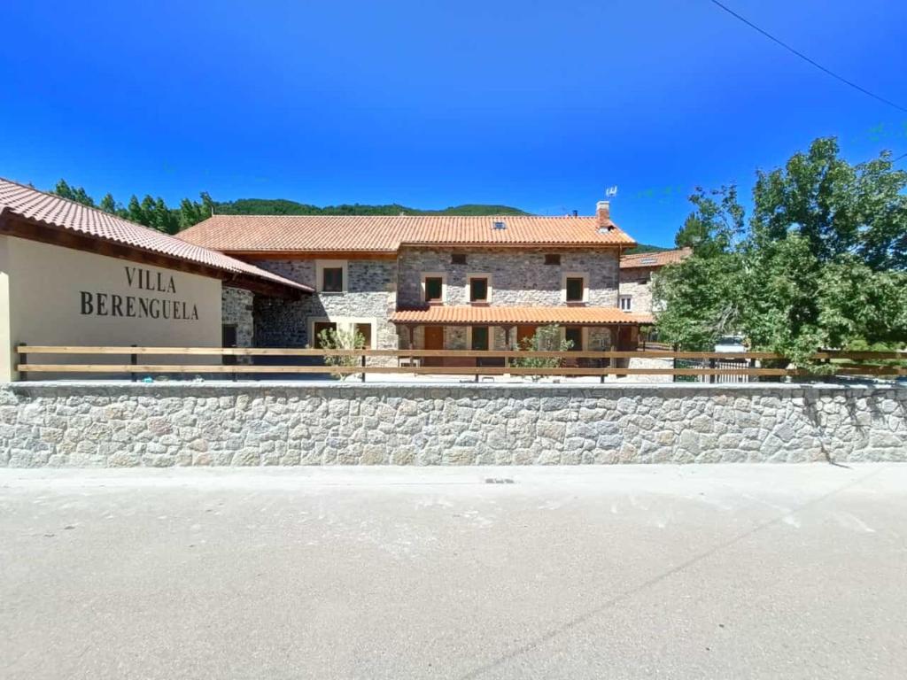 a building with a stone wall in front of a building at VILLA BERENGUELA in Boca de Huérgano