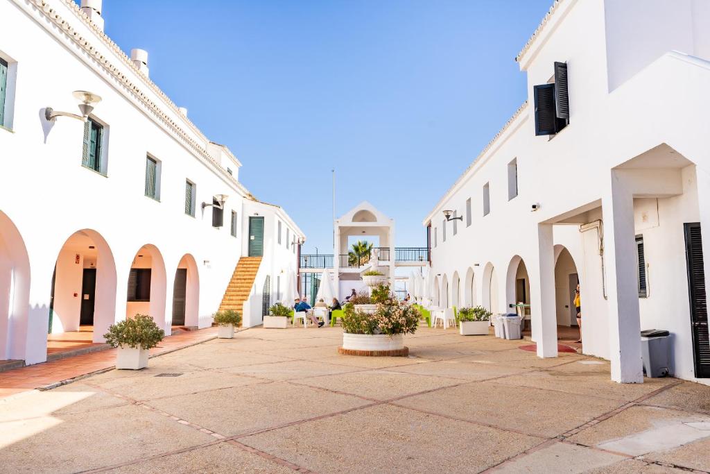 un patio con edificios blancos y macetas en Albergue Inturjoven Punta Umbría, en Punta Umbría