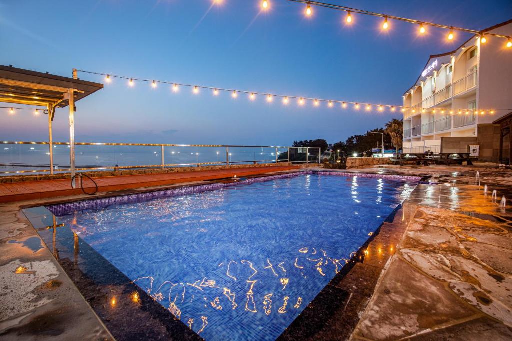 a swimming pool in front of a building with lights at Aewol Oceanstay in Jeju