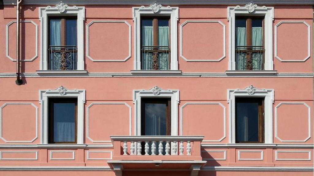 a pink building with windows and a balcony at Casa Calicantus in Milan