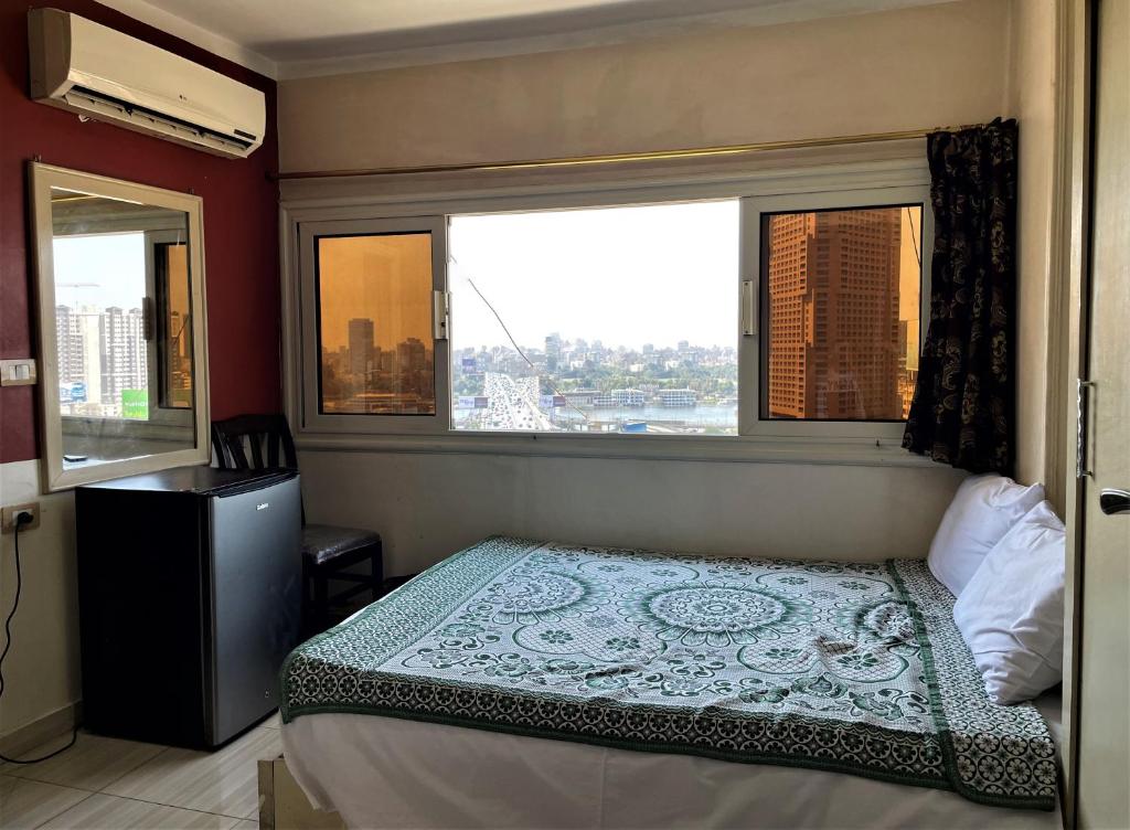 a small bedroom with a bed and two windows at Isis Hostel 2 in Cairo