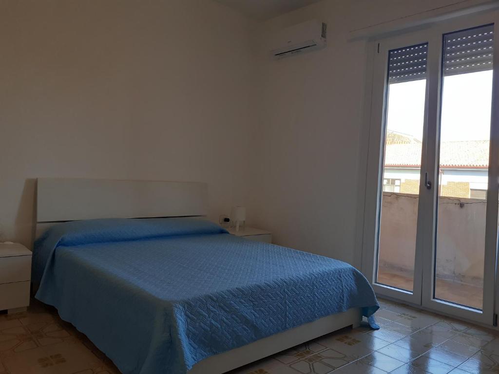 ein Schlafzimmer mit einem blauen Bett und einem großen Fenster in der Unterkunft Casa di Andy in Cagliari