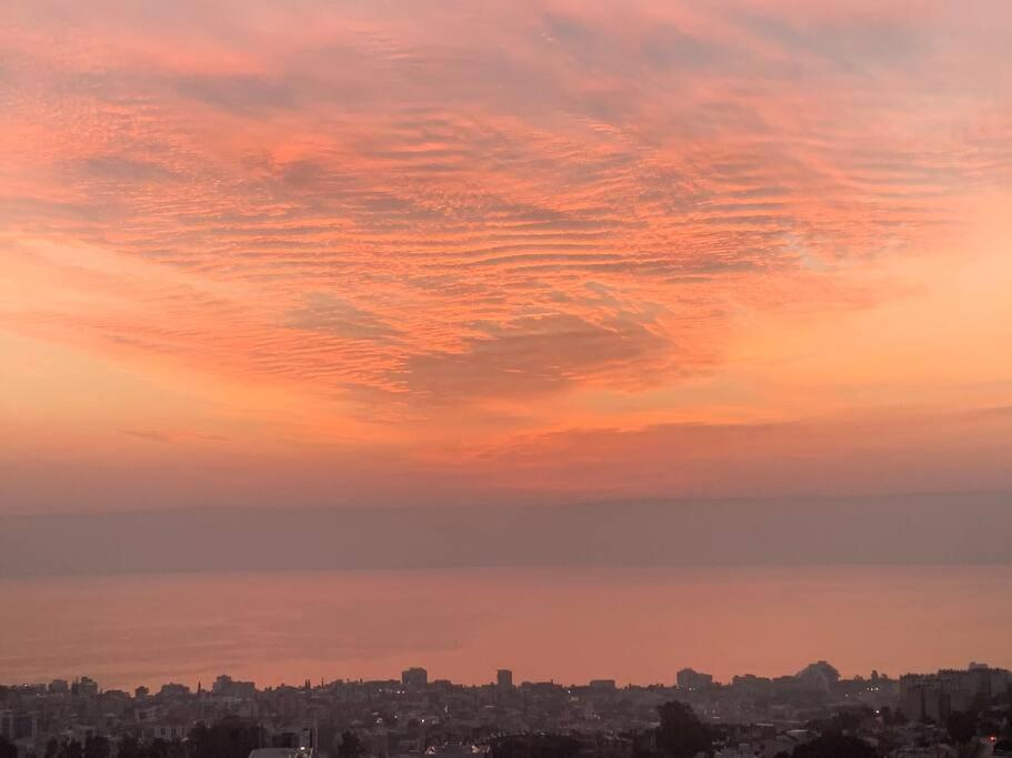 a sunset with a city in the background at Sea of Galilee Tiberius apartment with panoramic sea view in Tiberias