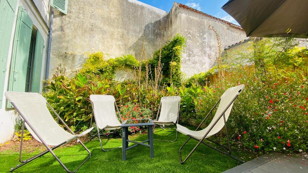 a group of chairs and an umbrella in a yard at Superbe appartement en plein centre village in Saint-Martin-de-Ré