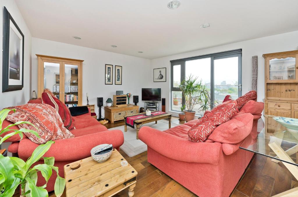 a living room with two red couches and a tv at Superb apartment with terrace near the river in Putney by UnderTheDoormat in London