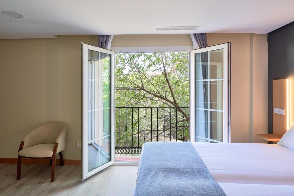 ein Schlafzimmer mit einem Bett und einem Balkon in der Unterkunft Smart Hotel La Sagra in Yuncos