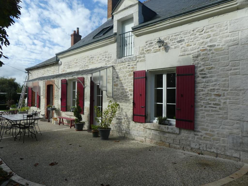 a white brick building with red shutters and a table at Chambre d'hotes "Les Paturelles" in Fougères-sur-Bièvre