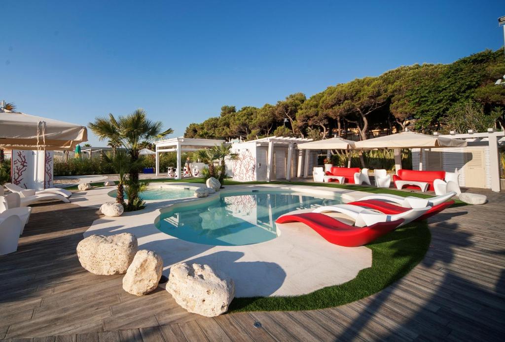 basen z czerwoną kanapą i krzesłami obok niego w obiekcie Hotel Doge w miejscowości Alba Adriatica