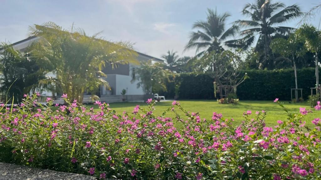 ein Haus mit rosa Blumen vor einem Hof in der Unterkunft Happy House in Cha-am