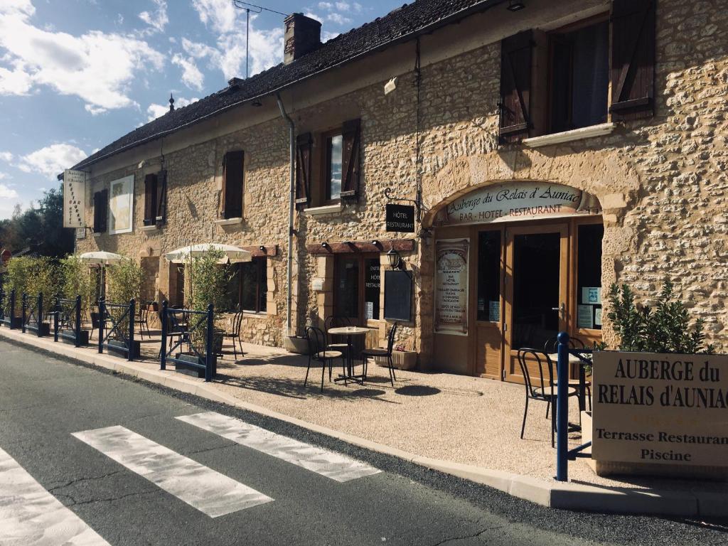 a building with tables and chairs on the side of the street at Auberge du relais d auniac Hotel Bar Restaurant Piscine in Anglars-Nozac