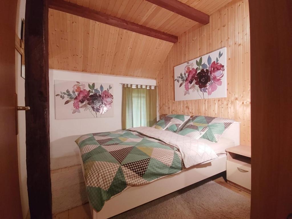 ein Schlafzimmer mit einem Bett in einem Holzzimmer in der Unterkunft Holiday House Trnovac in Trnovdc