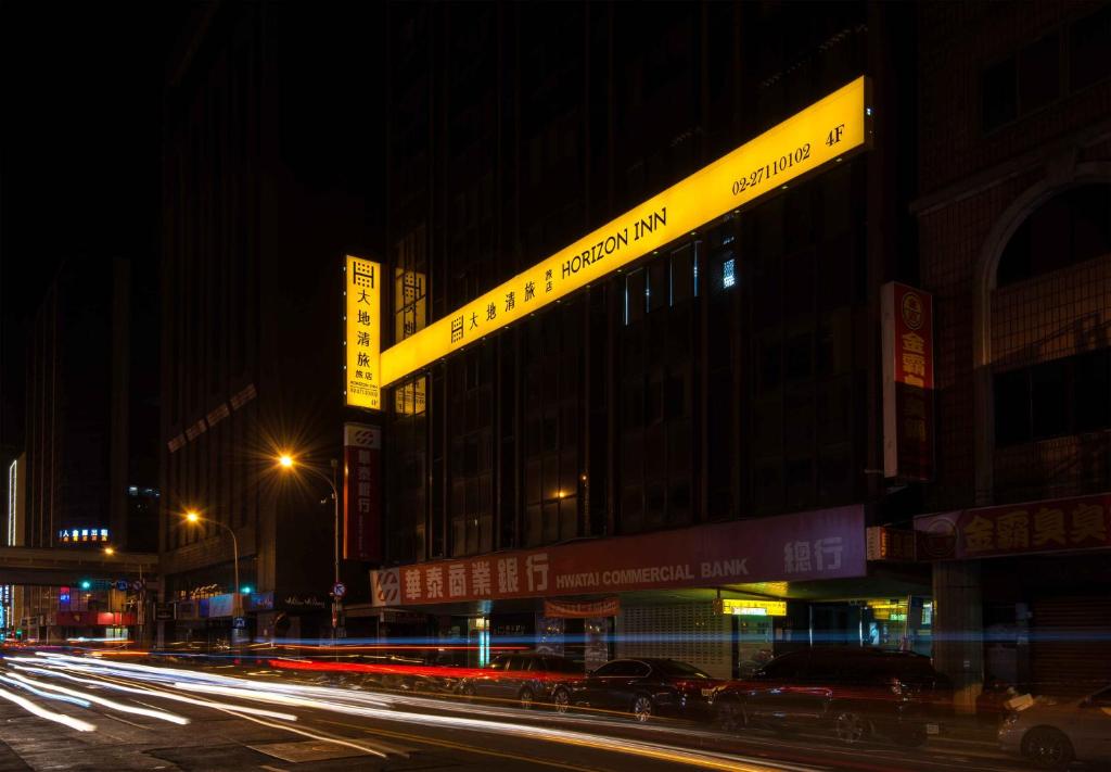 eine Stadtstraße in der Nacht mit Gebäuden und Lichtern in der Unterkunft Horizon Inn in Taipeh