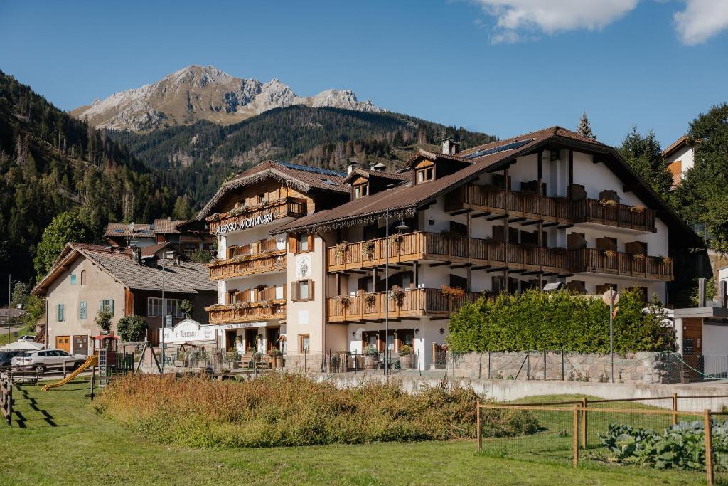 a large apartment building with a mountain in the background at Hotel La Montanara Predazzo in Predazzo