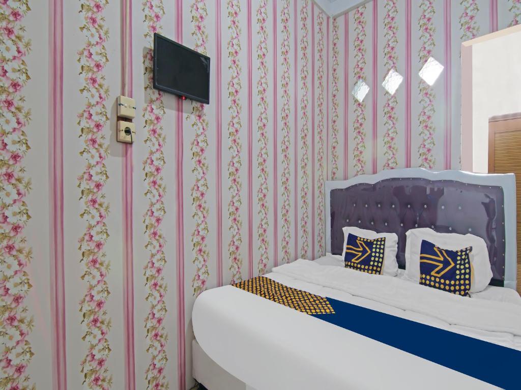 - une chambre avec un lit et une télévision murale dans l'établissement OYO 91826 Yoezef Homestay Syariah, à Pekanbaru