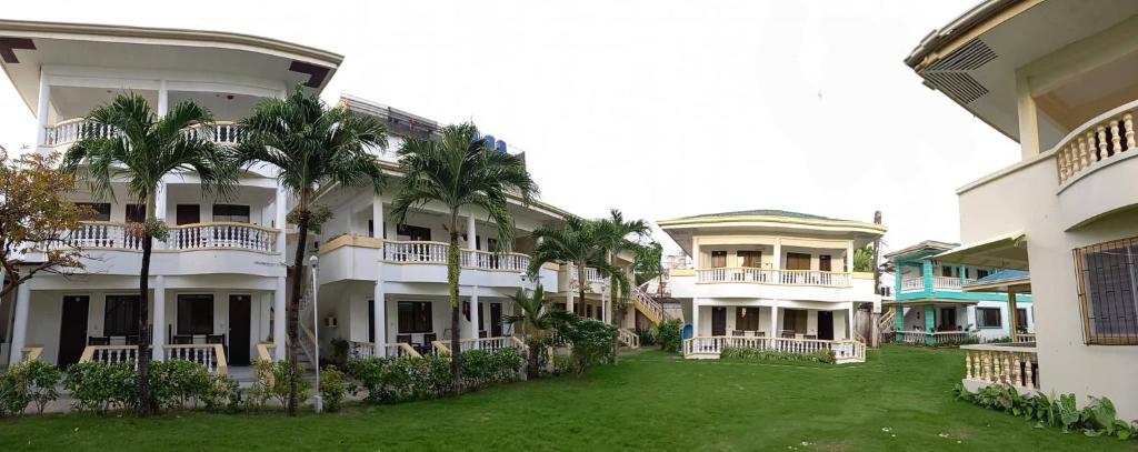 a large white building with palm trees in the yard at Bans Beach Resort in Boracay