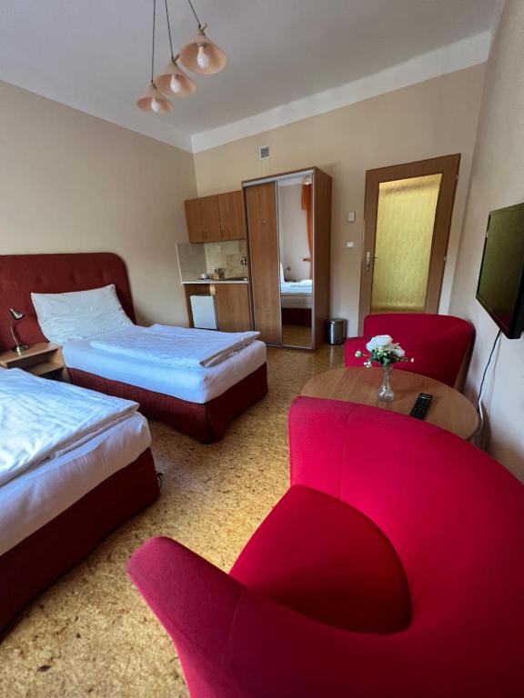 um quarto de hotel com duas camas e um sofá vermelho em Penzion Greenstar em Ústí nad Labem