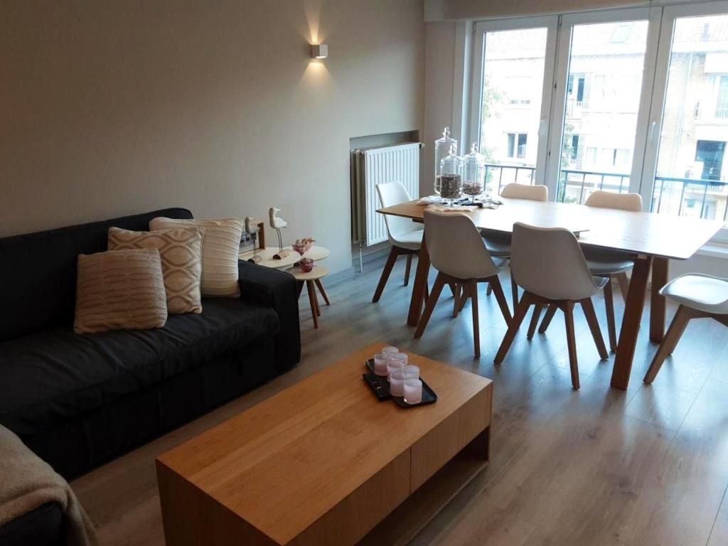 een woonkamer met een zwarte bank en een tafel bij 2 bedrooms appartement with city view balcony and wifi at Knokke Heist in Zeebrugge