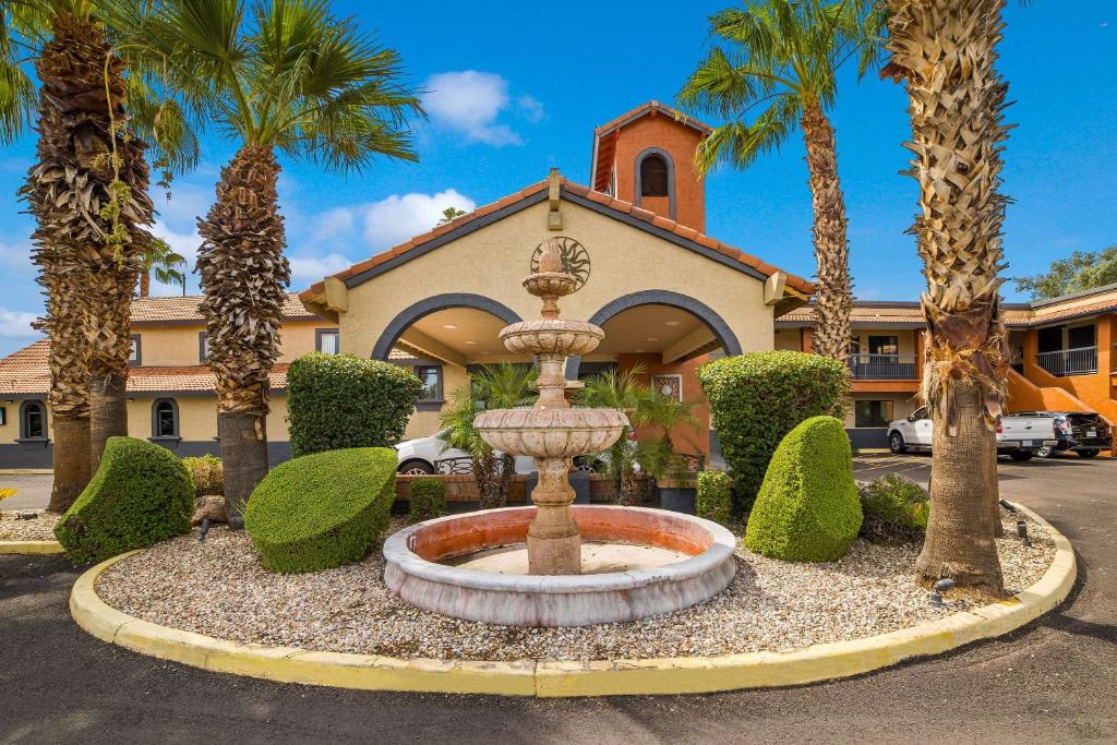 a fountain in front of a building with palm trees at Quality Inn & Suites Goodyear - Phoenix West in Goodyear