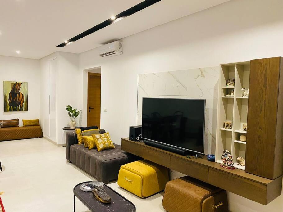 - un salon avec une grande télévision et un canapé dans l'établissement Sousse Sahloul apartment de luxe 10 min de la mer, à Sousse
